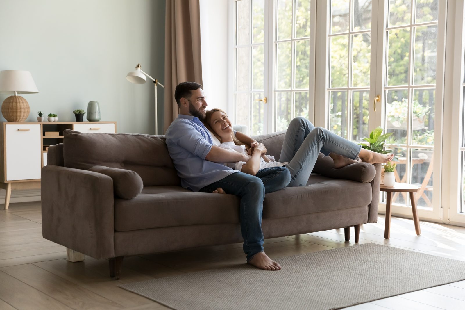 A couple relaxing together on a couch in a bright living room